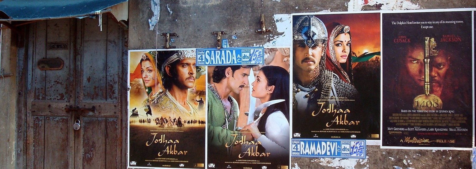 Hindi film posters pasted on a weathered wall beside an old wooden door